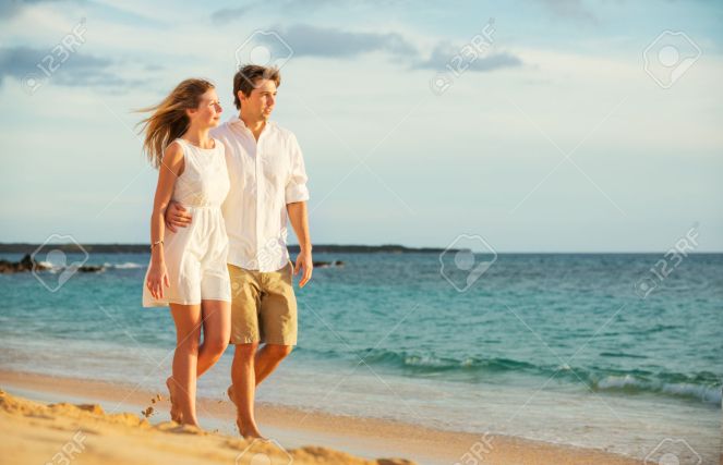 Young couple in love walking on the beach at sunset
